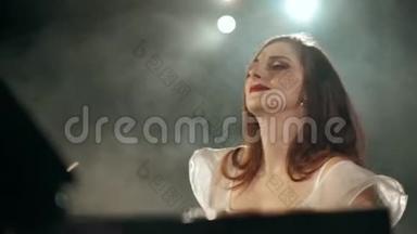 美丽的年轻女子穿着连衣裙在舞台上制作钢琴音乐。 4K段